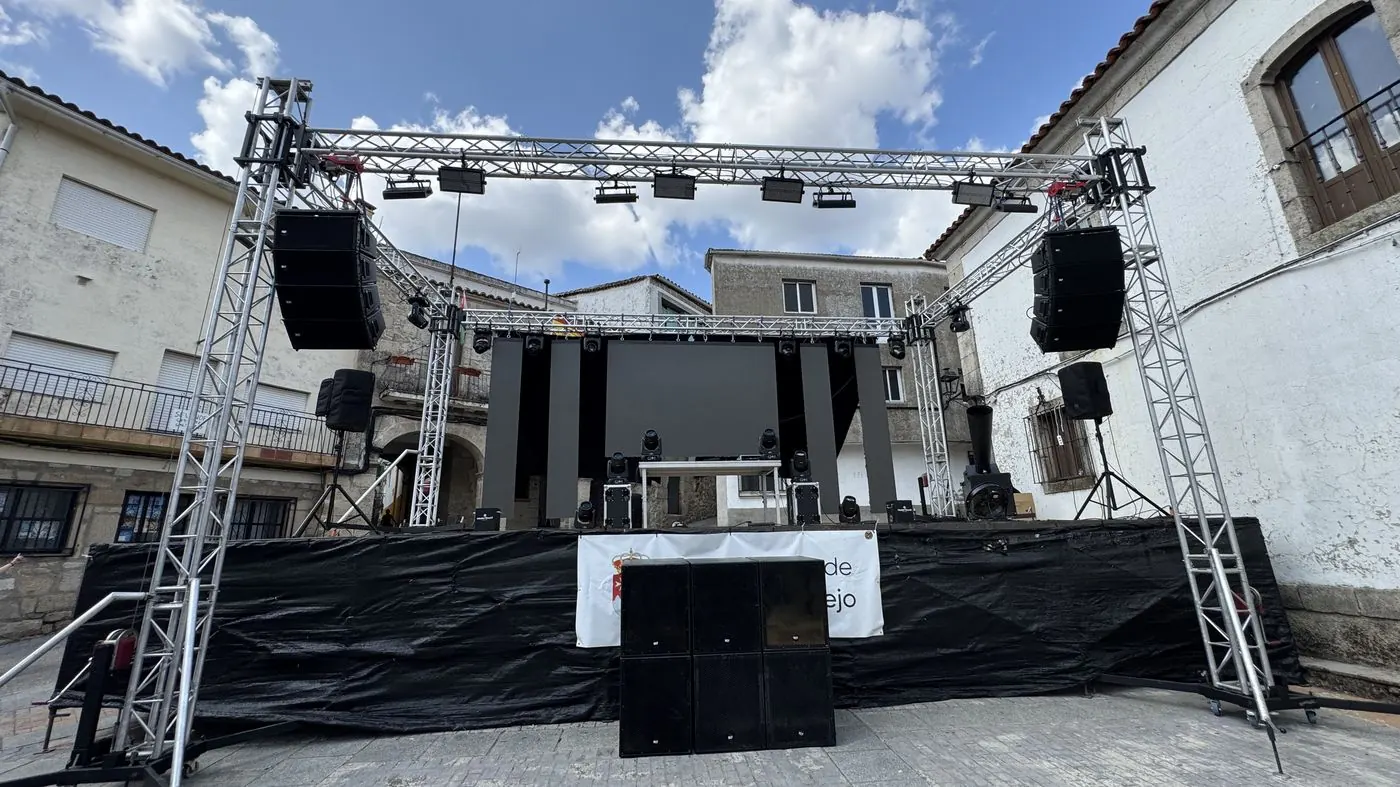 Escenario al aire libre con pantalla LED, estructura de iluminación y altavoces en una plaza